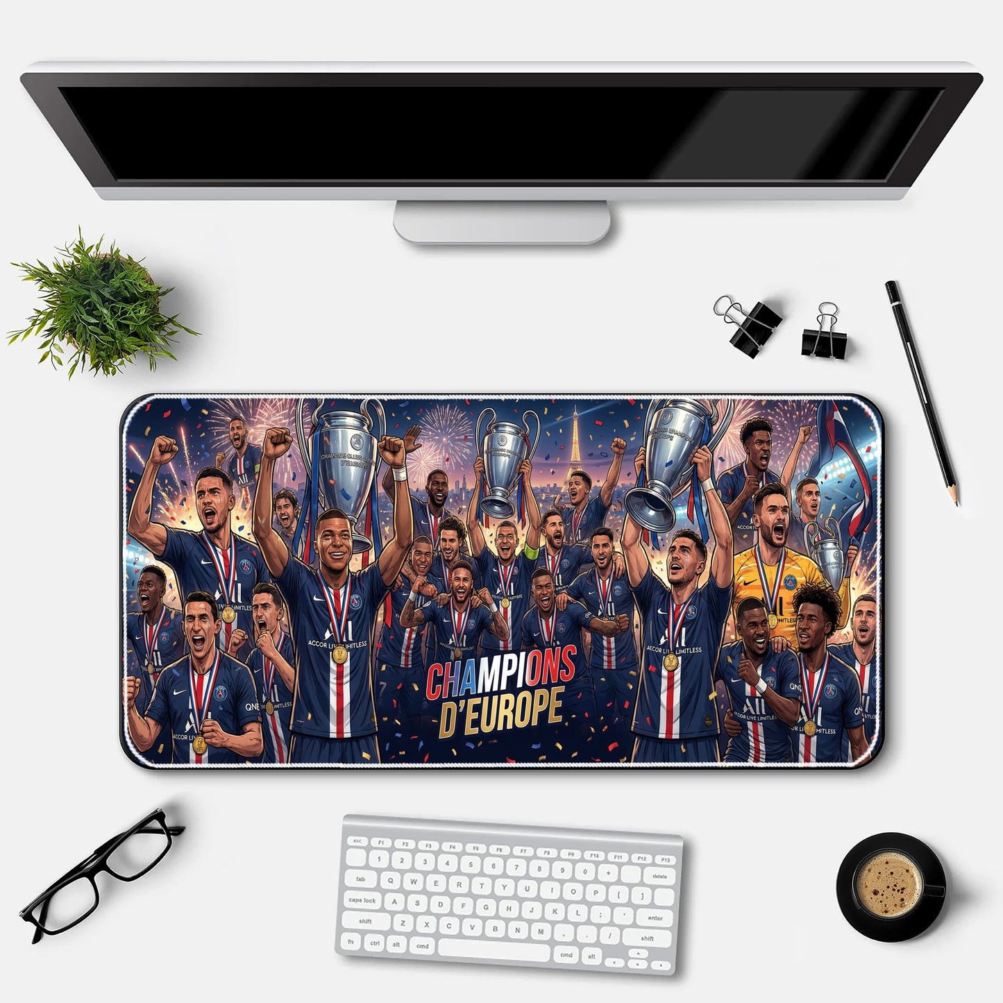 Desk setup with a large mouse pad featuring a soccer team celebrating with trophies, a computer monitor, keyboard, and office supplies.