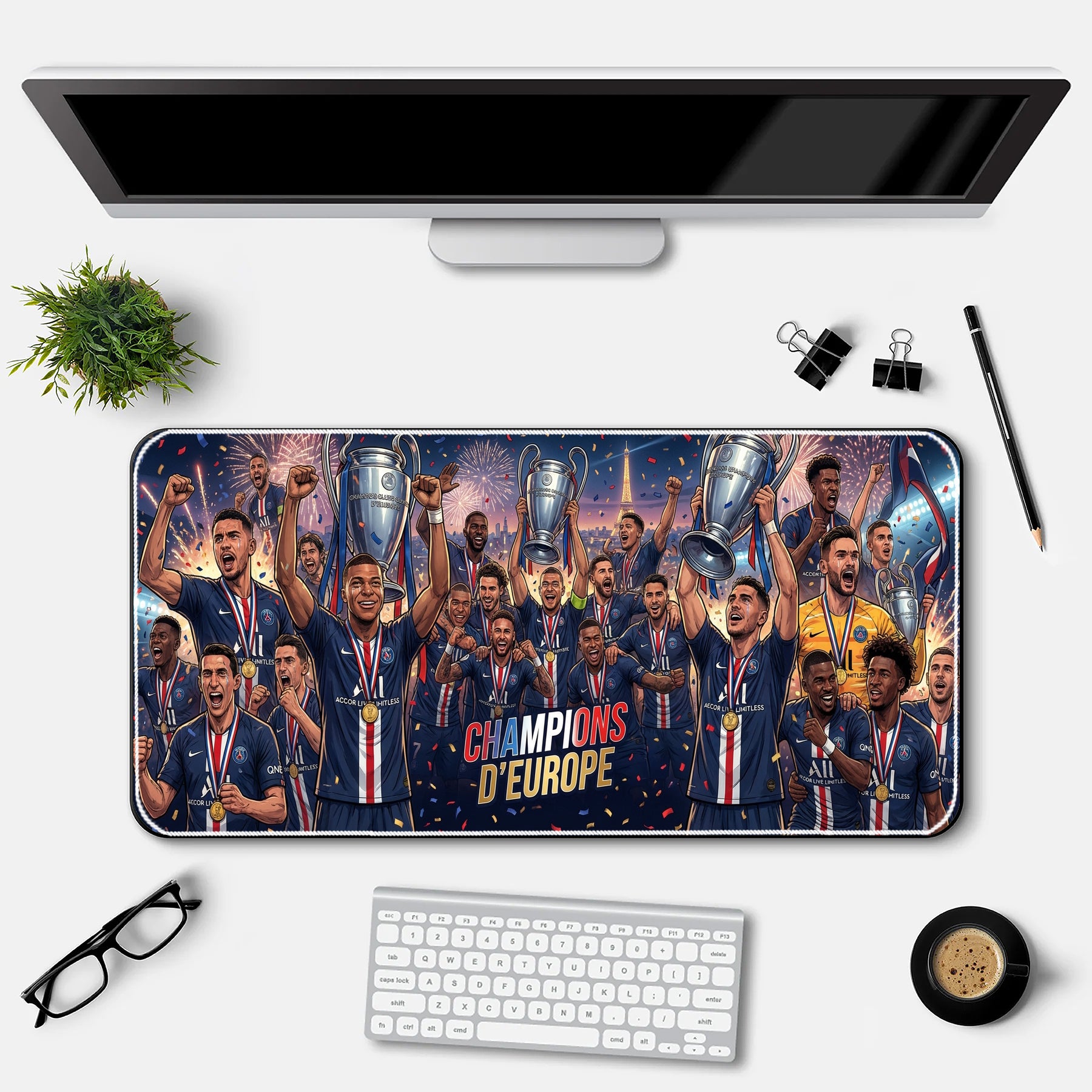 Desk setup with a large mouse pad featuring a soccer team celebrating with trophies, a computer monitor, keyboard, and office supplies.
