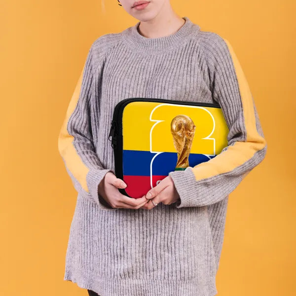 Person holding a bag with the World Cup trophy and Colombian flag design on an orange background