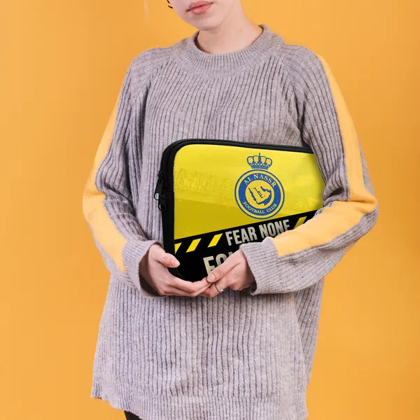 Person holding a yellow and black bag with a logo against an orange background