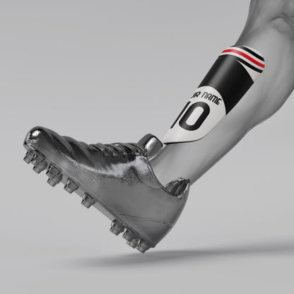 Silver soccer cleat with a black and red armband on a gray background