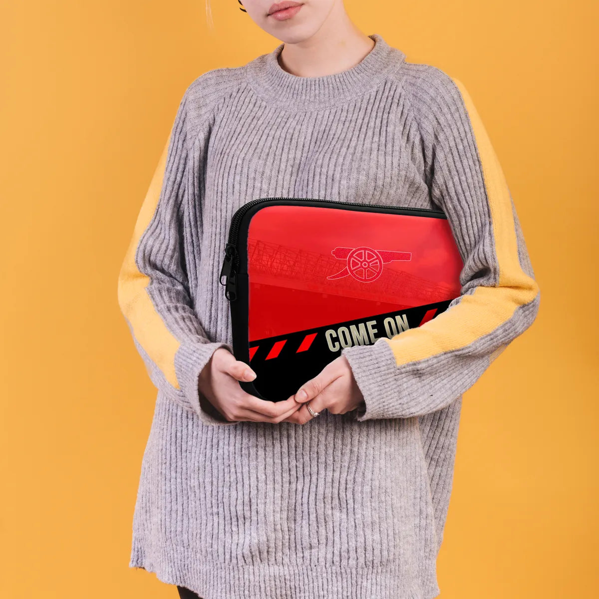 Person holding a red and black pouch with text against a yellow background