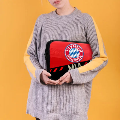 Person holding a red and black bag with FC Bayern Munich logo against a yellow background