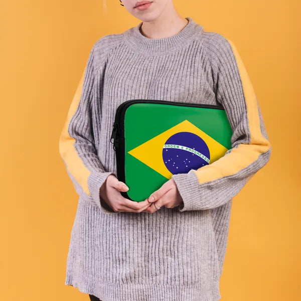 Person holding a laptop case with the Brazilian flag design against a yellow background