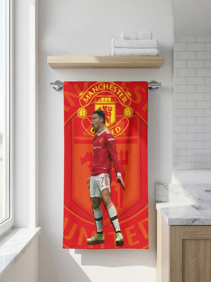 Man United towel with a player in red jersey hanging on a towel rack in a bathroom.