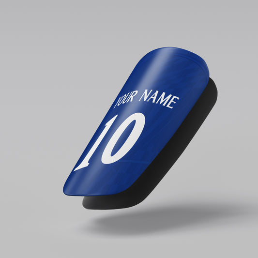 Blue shin guard with customizable name and number on a gray background