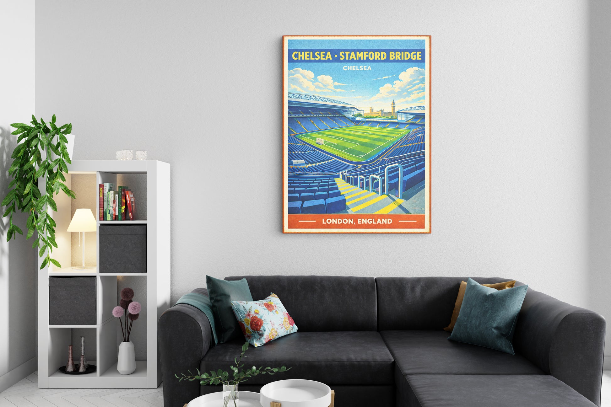 Living room with a gray sectional sofa and a framed poster of Chelsea Stamford Bridge on the wall.