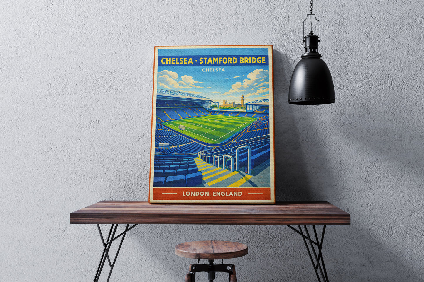 Framed poster of Stamford Bridge stadium on a wooden table against a gray wall.