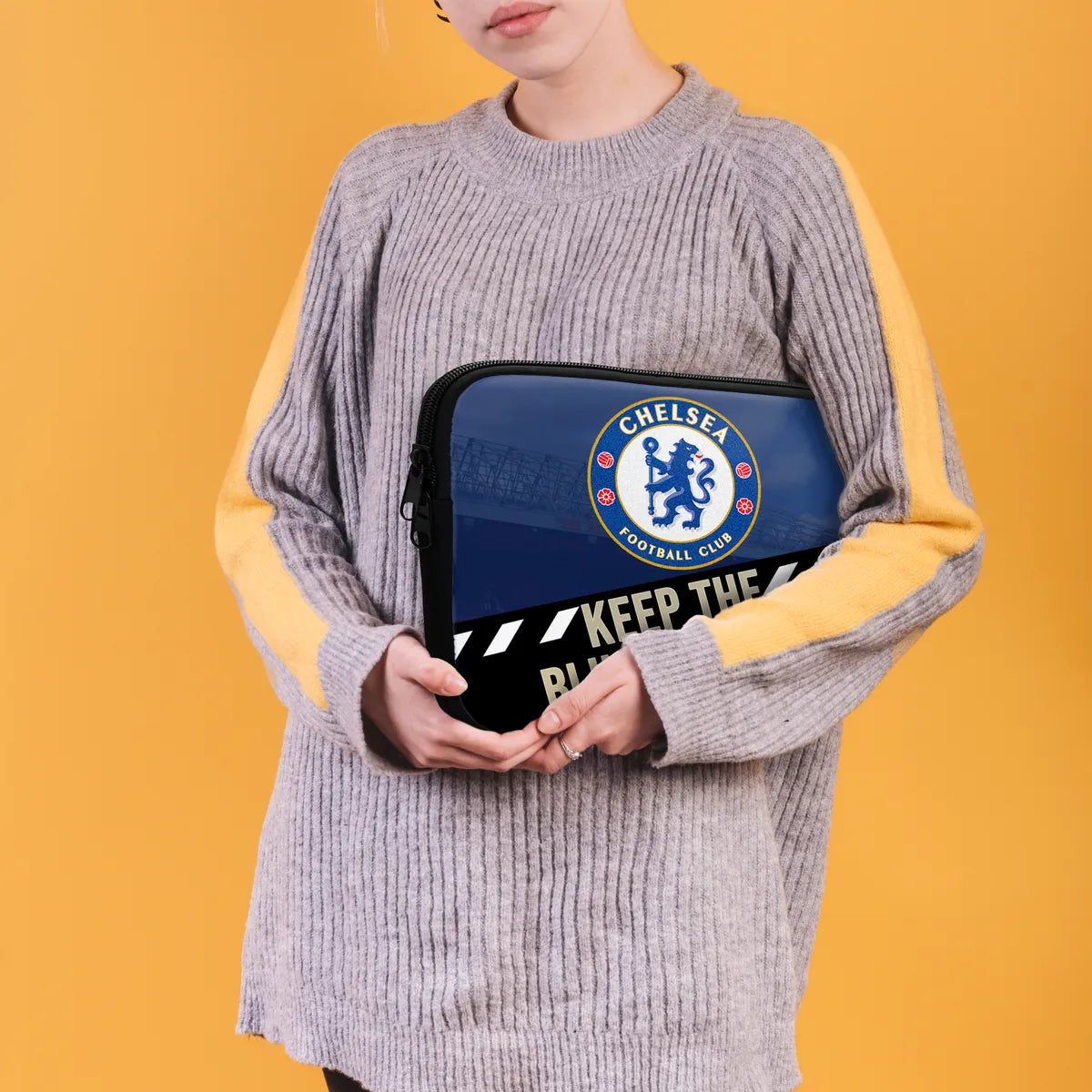 Person holding a Chelsea FC laptop case against a yellow background