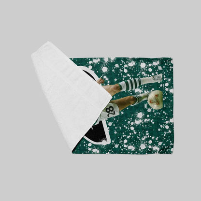 Soccer player in action on a green field with white splashes, wrapped in a white sheet.