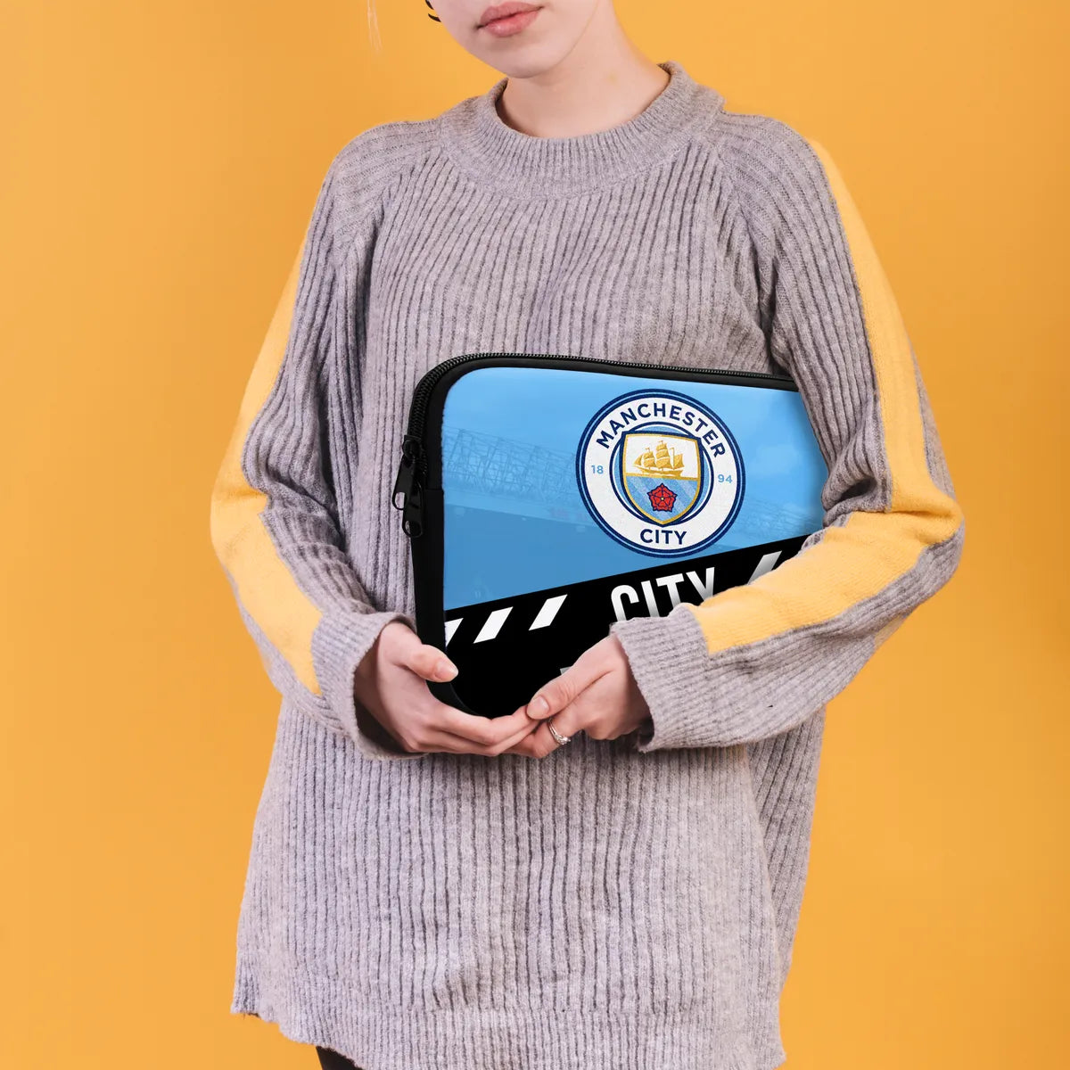 Person holding a Manchester City branded pouch against an orange background