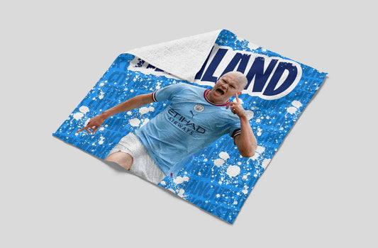 Child lying on a blue and white blanket with 'Man City' branding