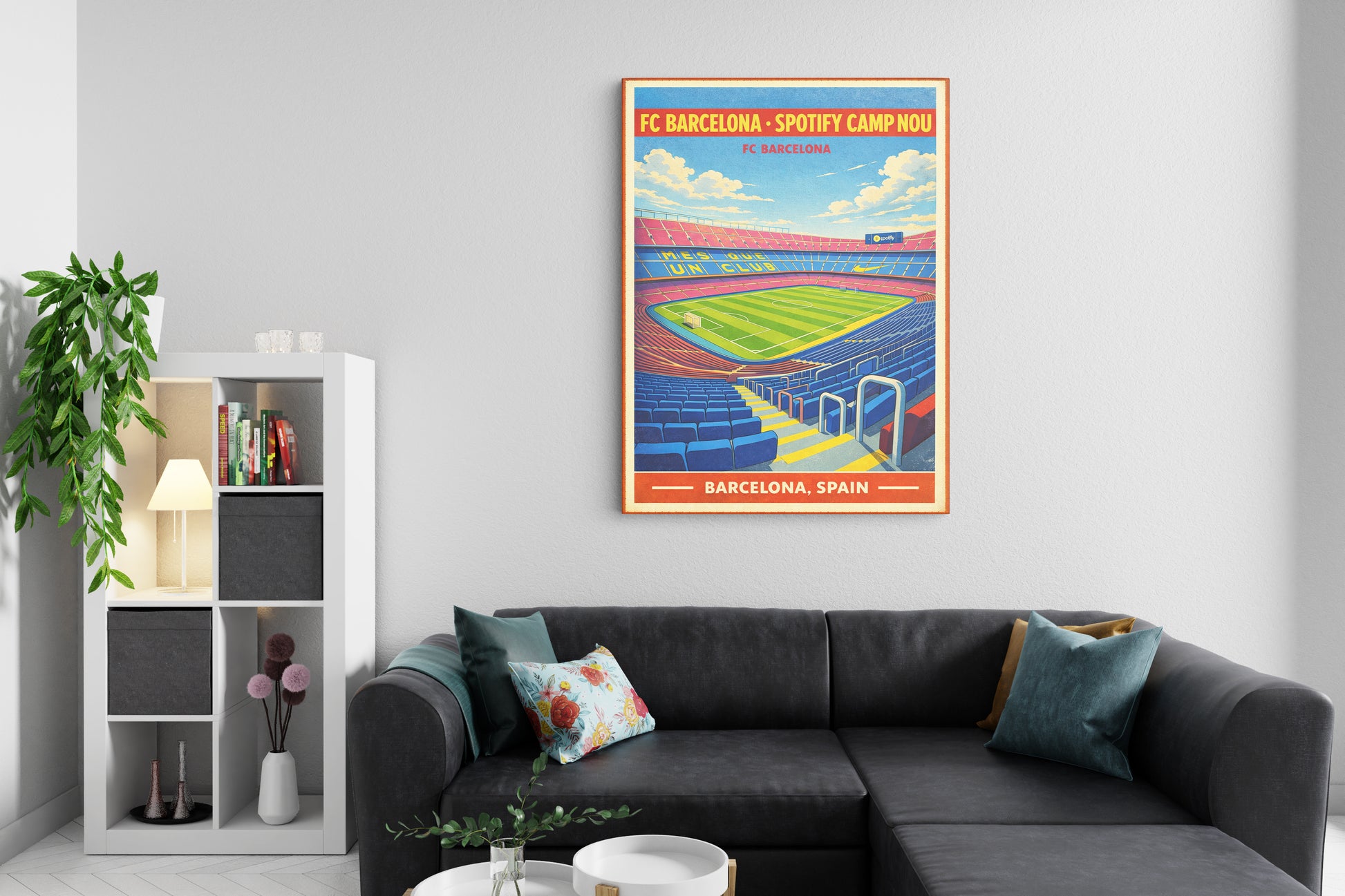 Living room with a gray sectional sofa, decorative pillows, and a framed poster of FC Barcelona's Camp Nou stadium on the wall.