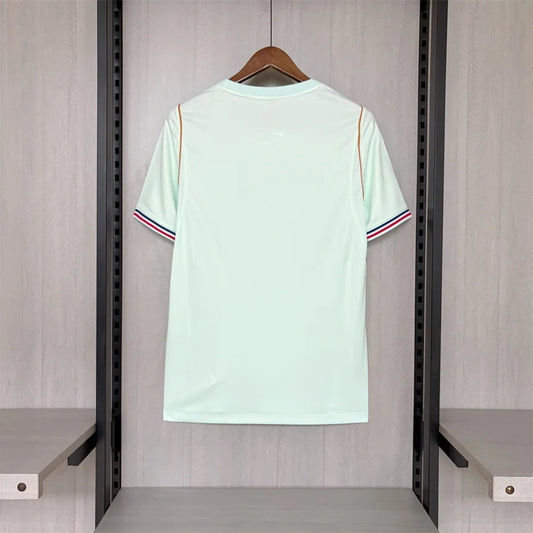 Light green t-shirt with red and blue stripes on a hanger against a neutral background