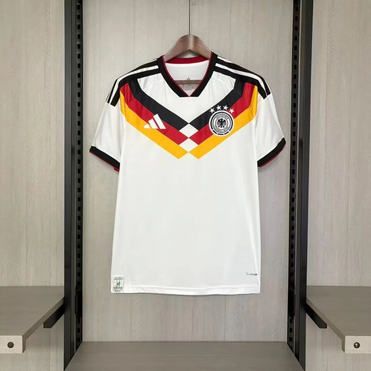White sports jersey with red, yellow, and black design hanging on a rack.