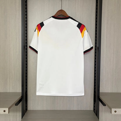 White sports jersey with red, yellow, and black accents on a hanger against a wooden panel background.