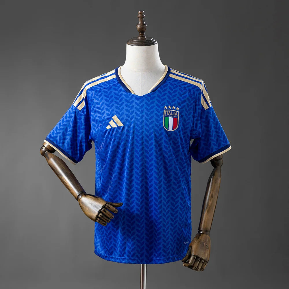 Blue sports jersey with Italian flag emblem on a mannequin against a gray background