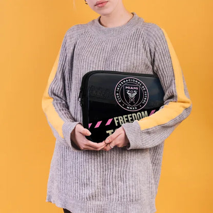 Person holding a black bag with branding against a yellow background