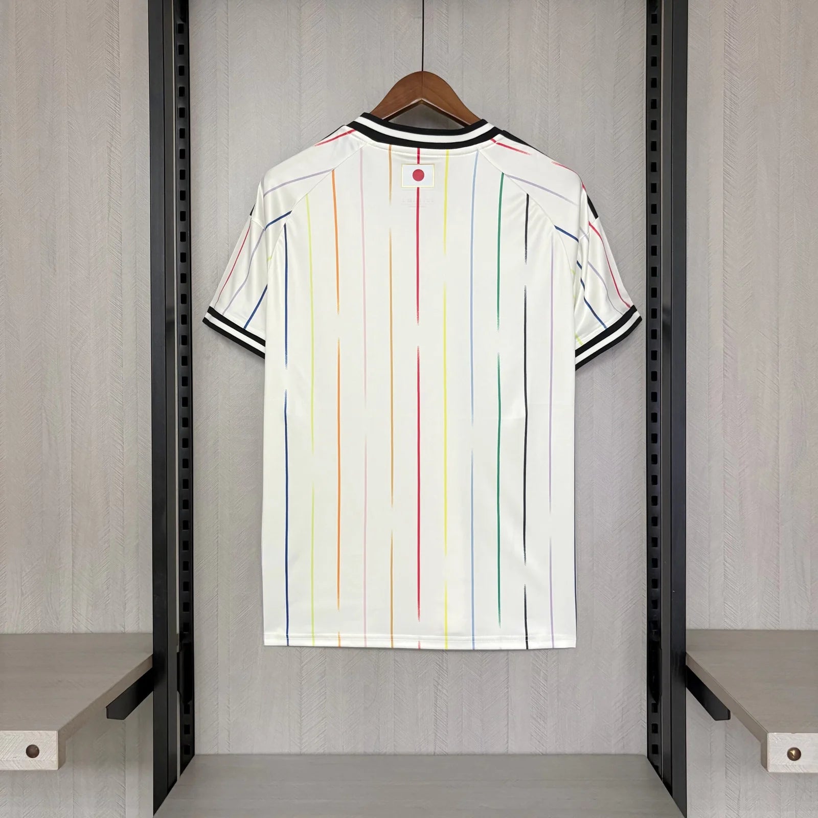 White shirt with colorful stripes hanging on a rack in a room.