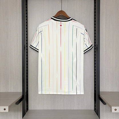 White shirt with colorful stripes hanging on a rack in a room.