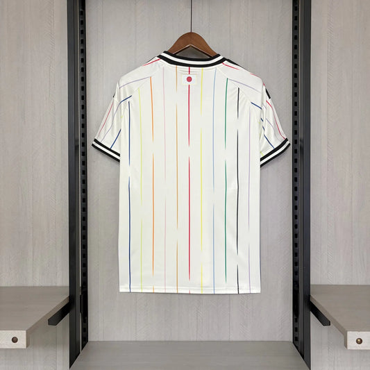 White shirt with colorful stripes hanging on a rack in a room.