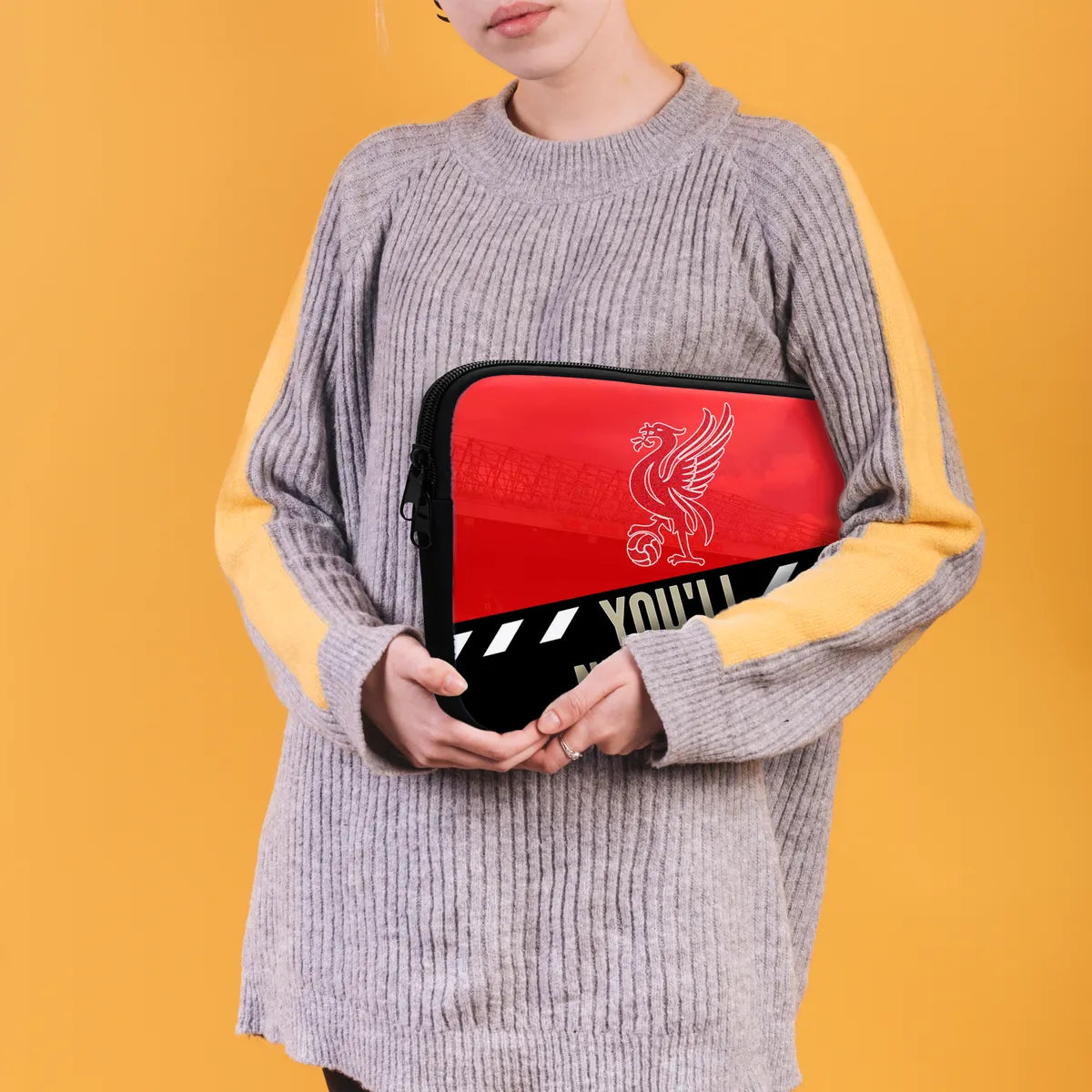 Person holding a red and black pouch with a logo against a yellow background