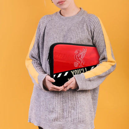 Person holding a red and black pouch with a logo against a yellow background