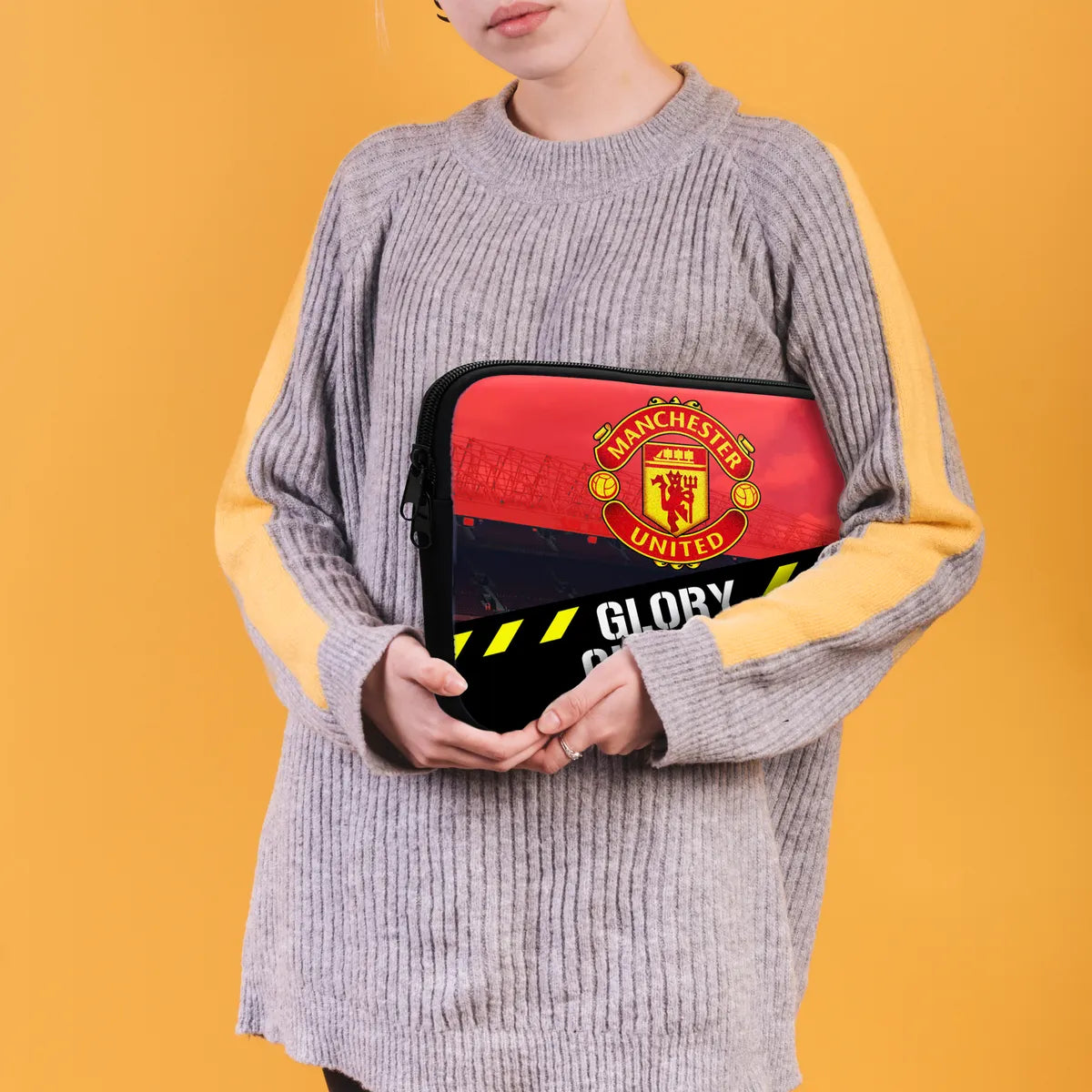 Person holding a Manchester United-themed pouch against a yellow background