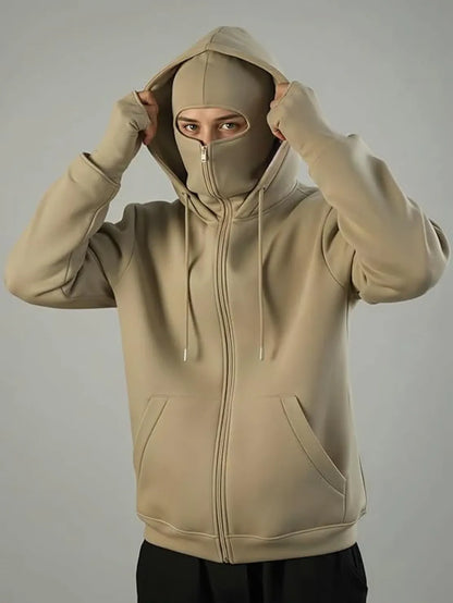 Beige hoodie with a face mask worn by a person on a gray background