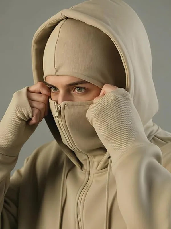 Person wearing a beige hoodie with a hood over their head against a neutral background