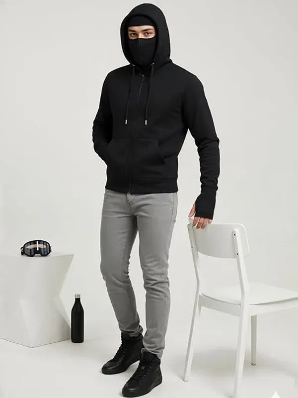 Person wearing a black hoodie and gray pants in a minimalistic setting