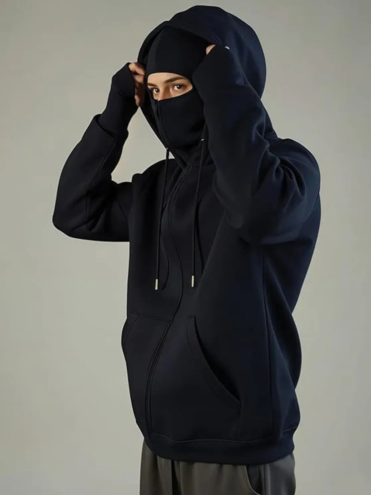 Person wearing a black hoodie and face mask against a neutral background