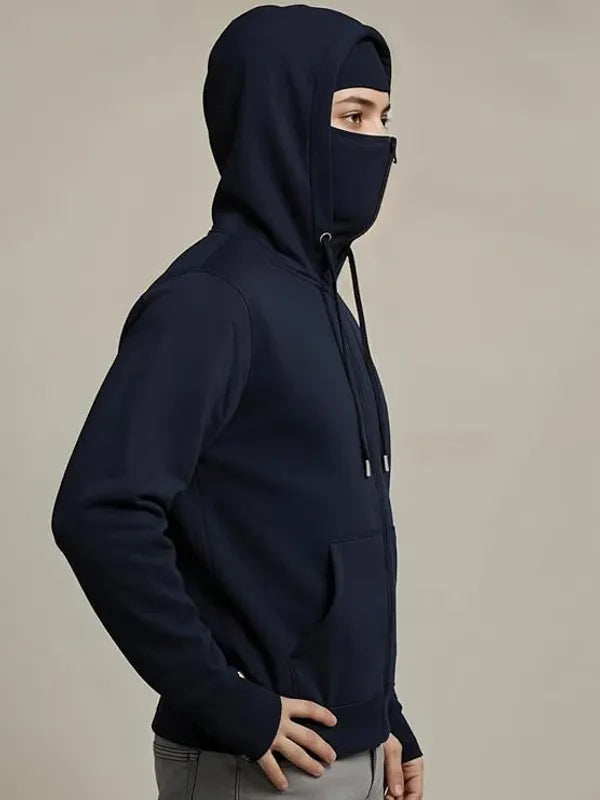 Person wearing a dark blue hoodie with a face covering on a beige background