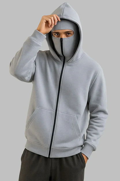 Person wearing a gray hoodie with a face mask underneath on a plain background