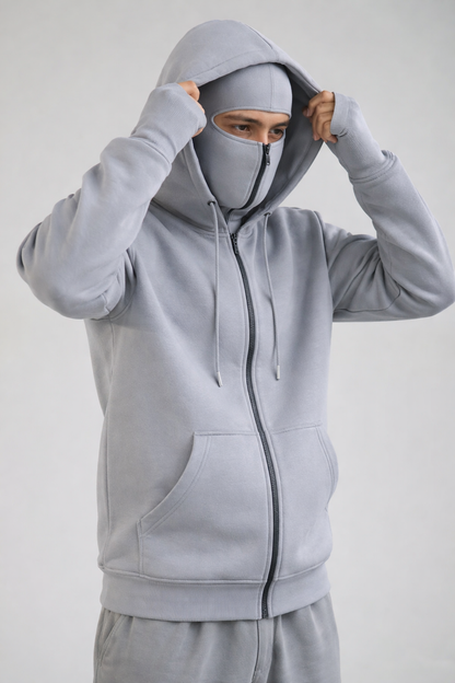 Person wearing a gray hoodie with a face covering on a white background