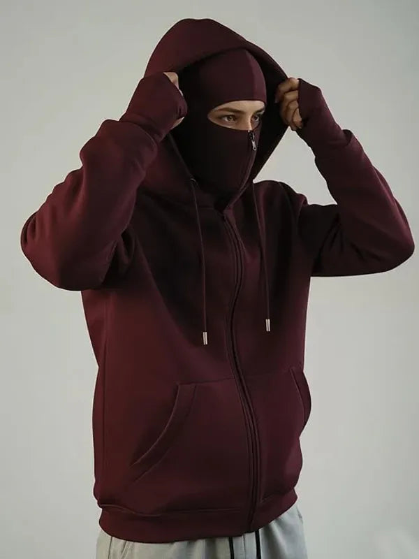 Person wearing a maroon hoodie with a matching face cover against a plain background
