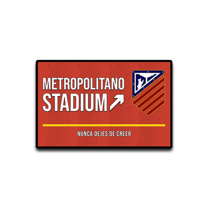 Red sign with 'Metropolitano Stadium' text and logo on a white background
