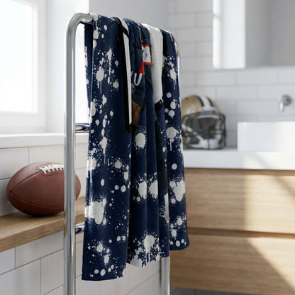 Bathroom with a towel rack holding a navy blue towel with white patterns, a football on a shelf, and a sink.