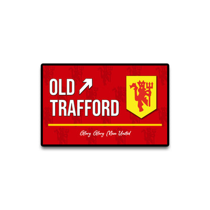 Red sign with 'Old Trafford' and a yellow logo on a white background