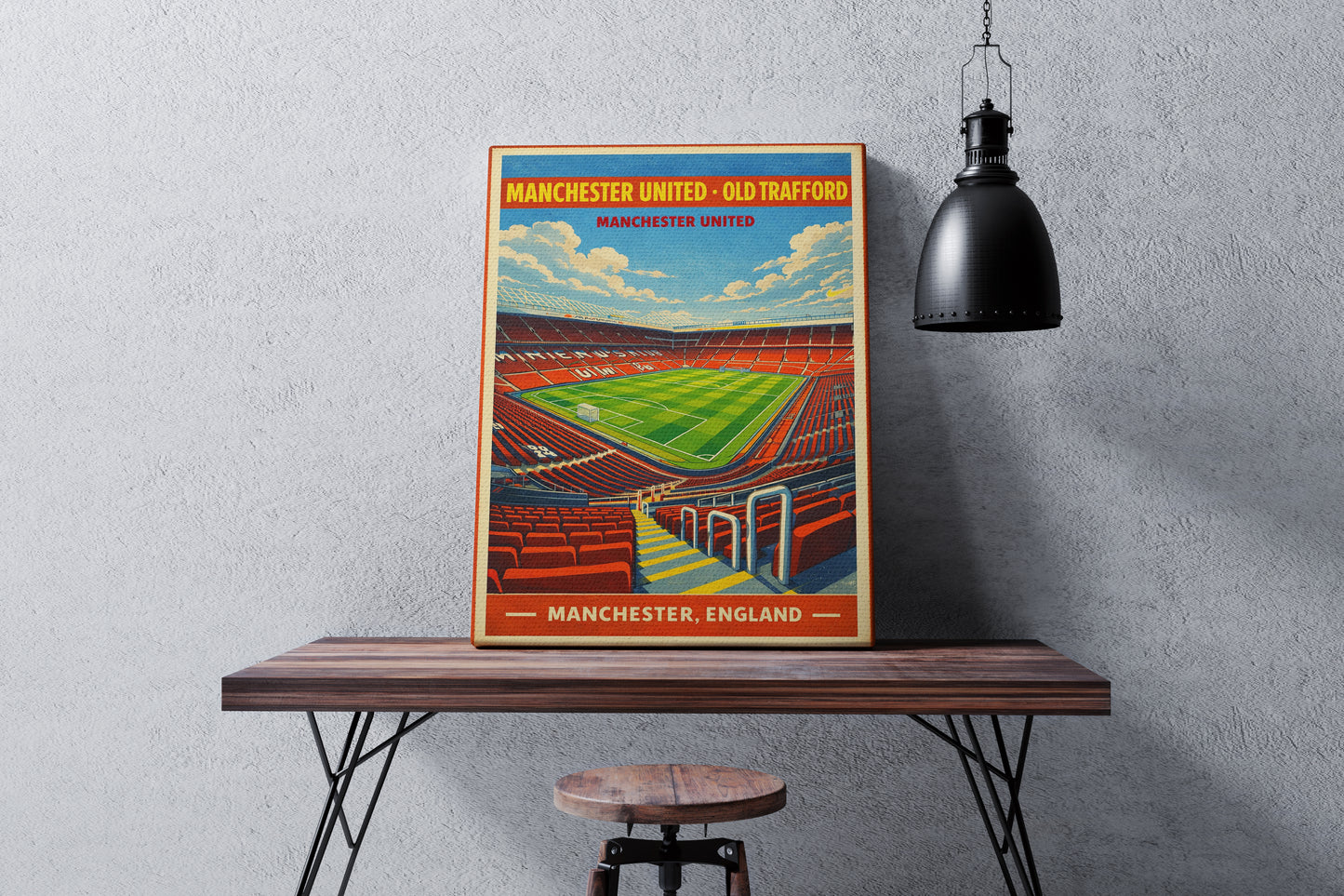 Poster of Manchester United's Old Trafford stadium on a wooden table against a gray wall.