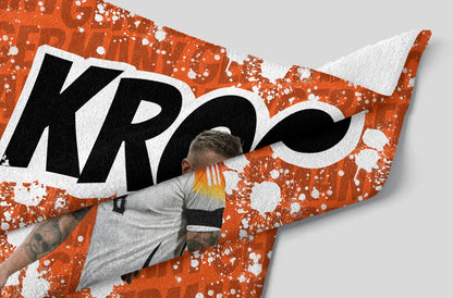 Person leaning against a large orange and white 'KROQ' logo on a gray background