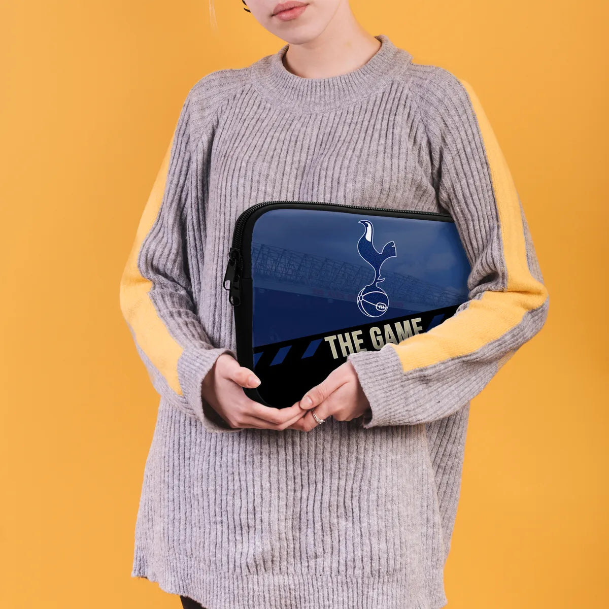 Person holding a laptop case with a logo and text on a yellow background