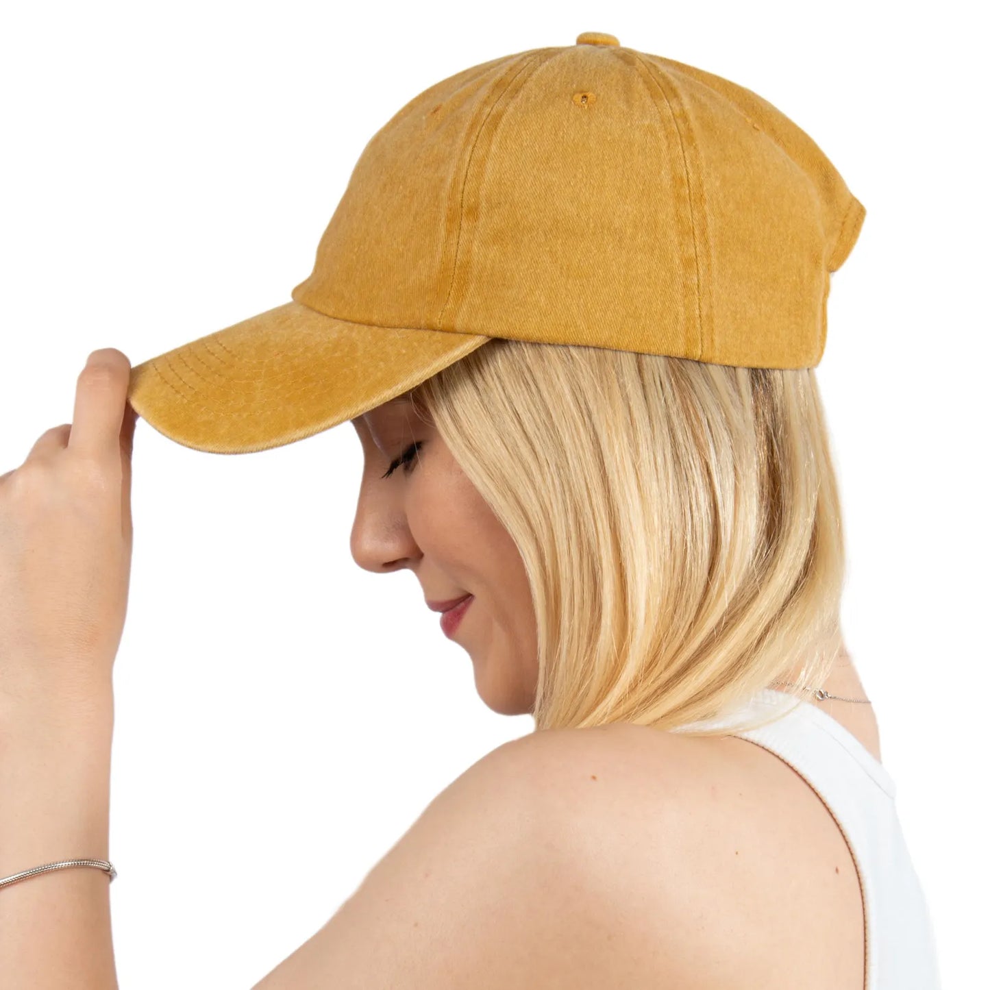 Woman wearing a mustard yellow baseball cap on a white background