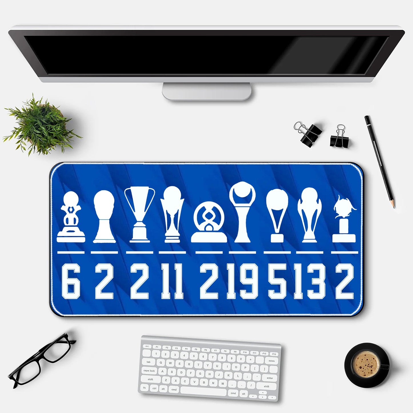 Desk setup with a blue desk mat featuring white icons and numbers, a computer monitor, keyboard, and office supplies.