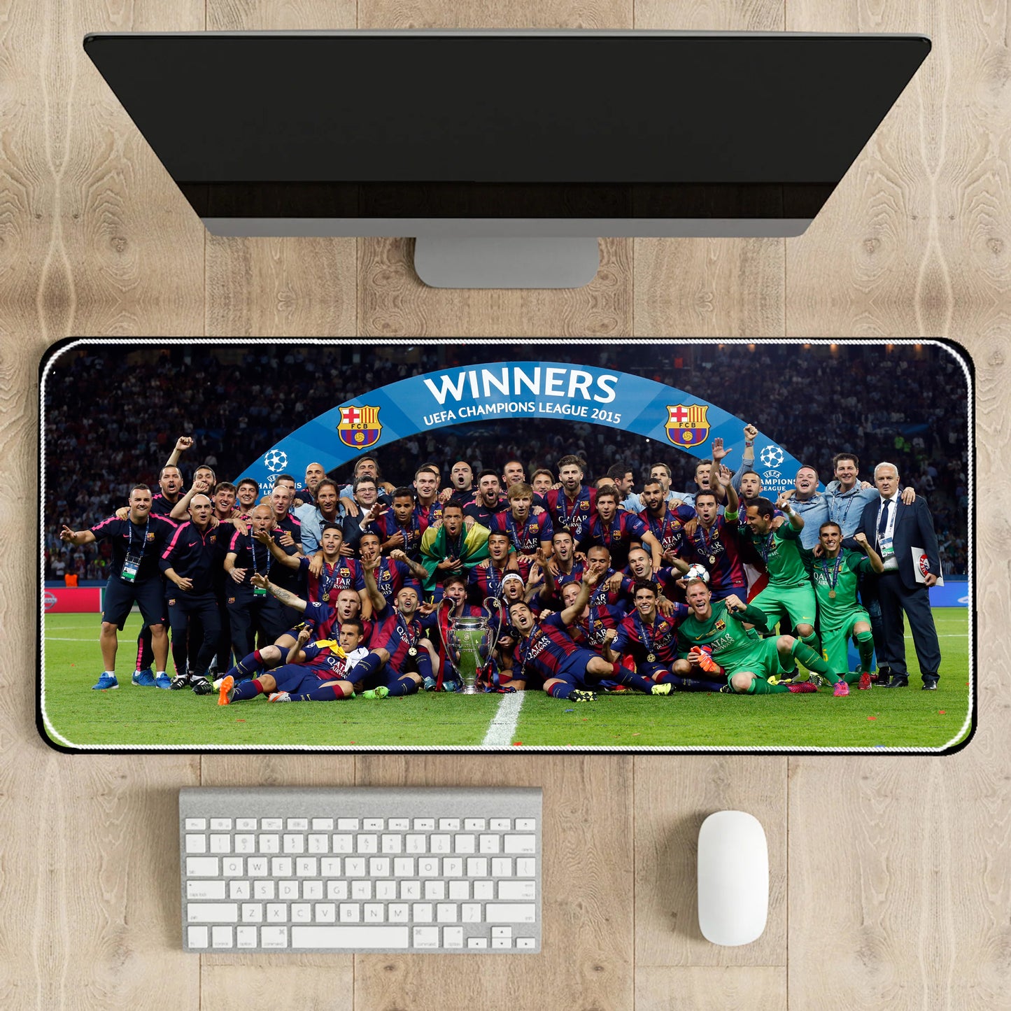 Desk setup with a large mouse pad featuring a soccer team celebration, keyboard, and mouse.