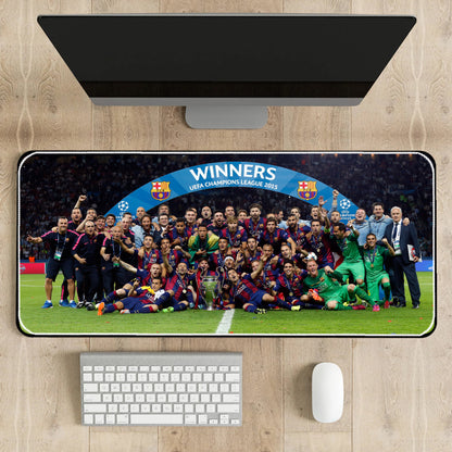 Desk setup with a large mouse pad featuring a soccer team celebration, keyboard, and mouse.