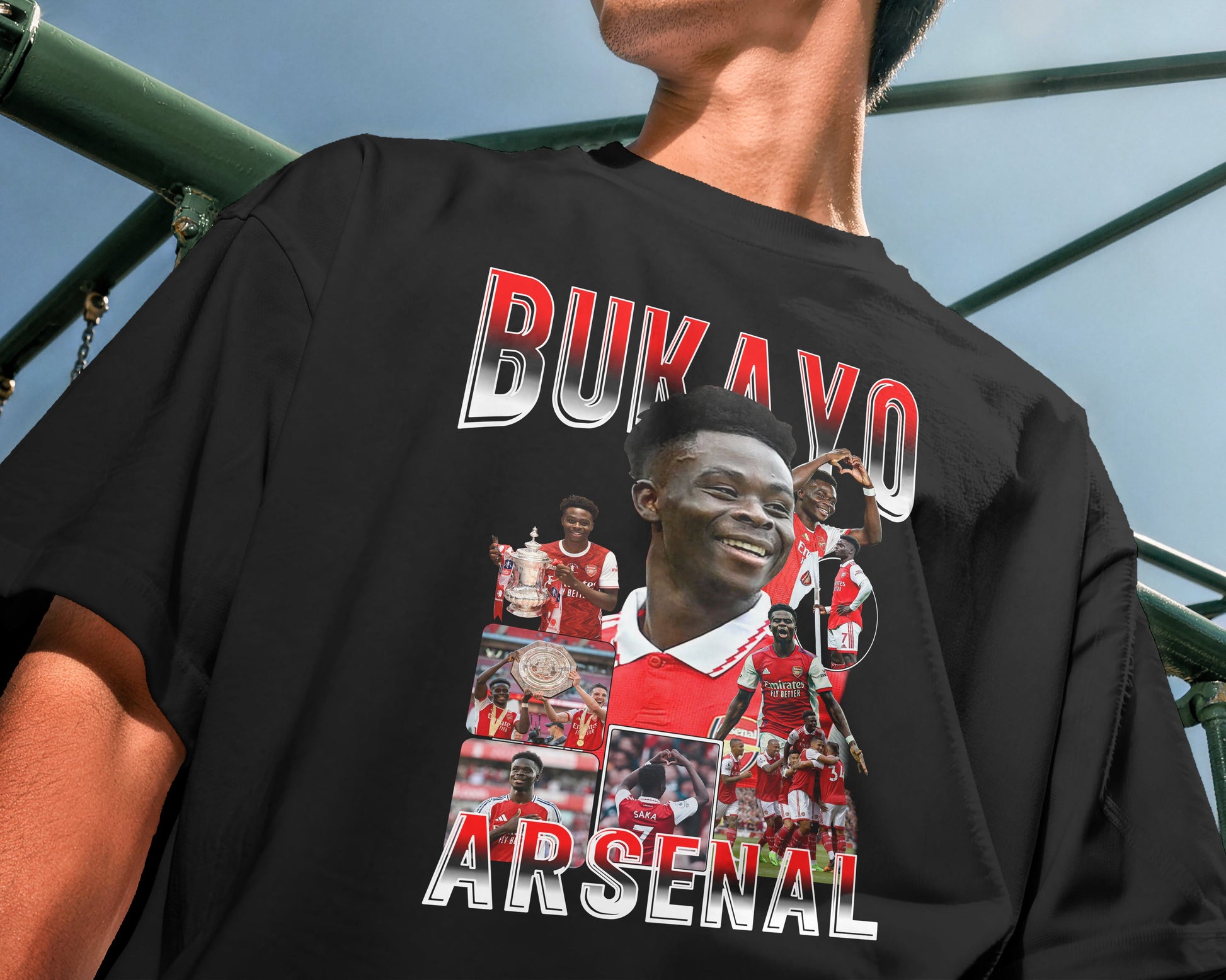 Person wearing a black t-shirt with 'Bukayo Arsenal' design outdoors.