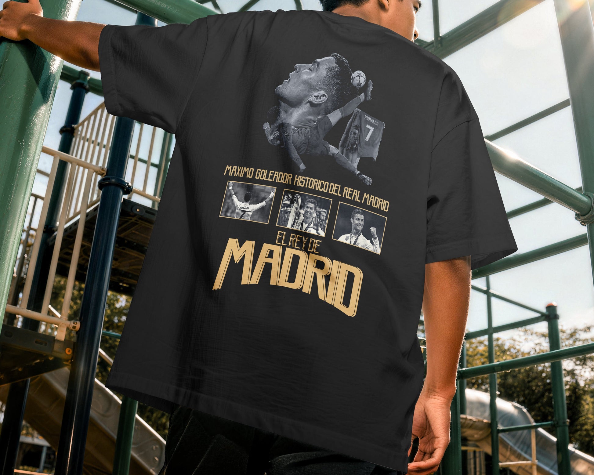 Person wearing a black t-shirt with graphic designs and text, standing outdoors.