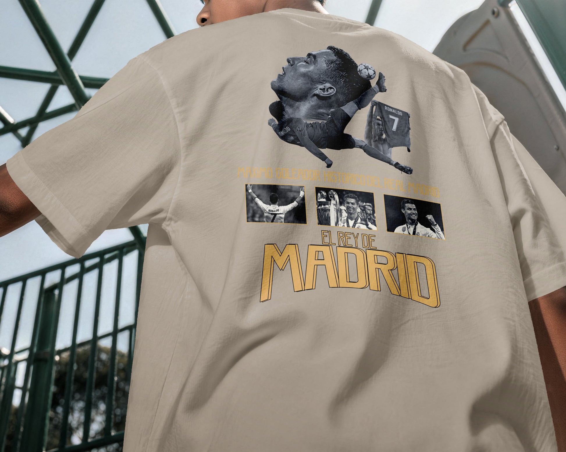 Beige t-shirt with graphic design and 'El Rey de Madrid' text on a person outdoors.