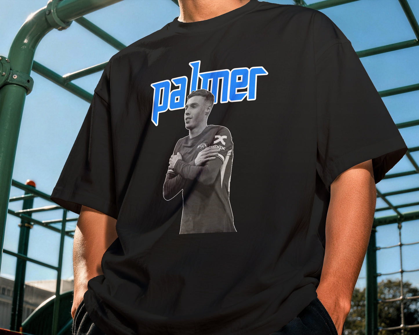 Person wearing a black t-shirt with a graphic and 'palmer' text outdoors.